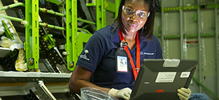Woman in safety glasses and rubber gloves working at laptop